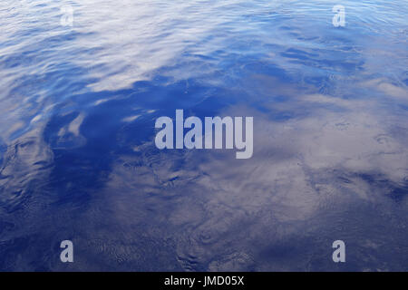 Smooth ocean surface reflecting clouds and sky with ripples Stock Photo