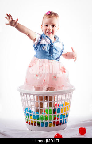 happy girl plays with color balls. standing in the laundry bag and smiling.. isolated on white background Stock Photo