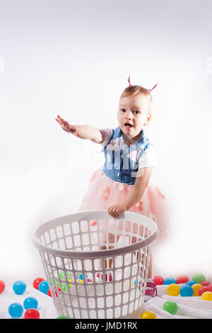 happy girl plays with color balls. standing in the laundry bag and smiling.. isolated on white background Stock Photo