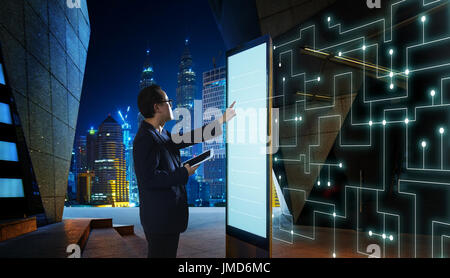 Smart businessman touch the screen to search the information of intelligent communication network of things . Night scene with modern city background  Stock Photo