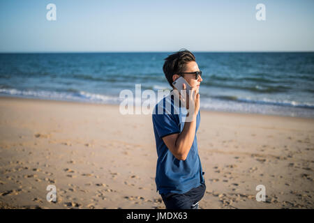 Young asian man  talking on phone and see the sunset on tropical beach Stock Photo