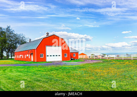 Red orange painted barn shed with white doors in summer landscape field in countryside Stock Photo