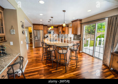 Upscale, spacious luxury kitchen with large granite top center island and stainless appliances and slider to open patio Stock Photo