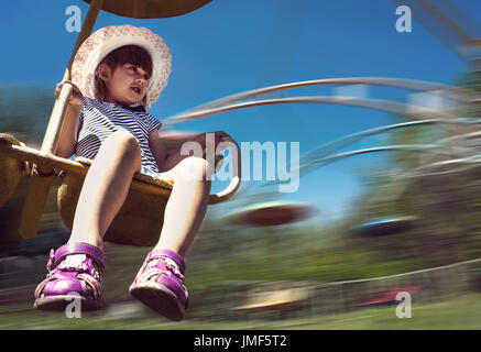 Happy girl having fun on the roundabout. a child is spinning on the carousel in the Park. the effect of motion blur Stock Photo