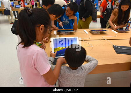 Two kids play on an iPad Air at the grand opening of the 1st Apple headquarters located in Taipei 101 building, Taipei, Taiwan. Stock Photo