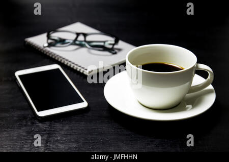 Coffee with notebook ,glasses and mobile phone on wood background. Stock Photo
