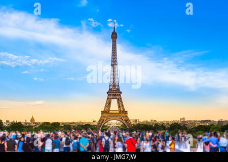 Colorful large group of unrecognizable people blurred in front of Paris Eiffel Tower at evening light (copy space) Stock Photo