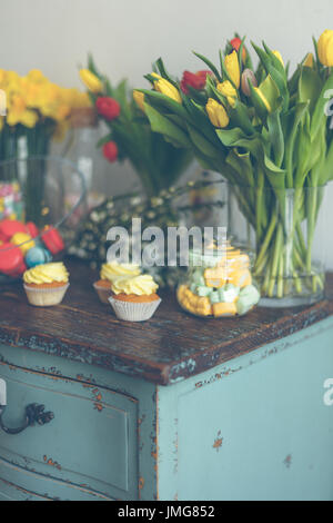 Bright macaroons and cupcakes on a wooden table. Indoors natural light shot with small depth of field Stock Photo