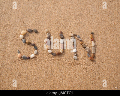 word sun written with stones and shells on the beach by the ocean Stock Photo