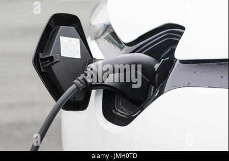 Car battery charging port with a small electric car plugged in while charging its batteries. Green energy concept. Stock Photo