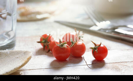Some cherry tomatoes on a white wooden table in a rustic kitchen. Empty copy space for Editor's text. Stock Photo