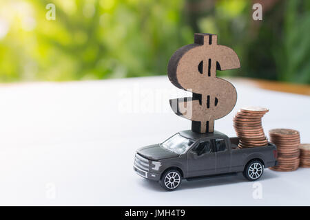 Miniature truck with dollar sign carrying stack of coins using as a business concept, saving concept. Stock Photo