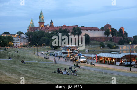 Many people sit on a meadow on the bank of the Vistula river in Krakow (Poland). In the background is Wawel Castle. Taken 22.06.2017. The Wawel is the former residence of the Polish royals in Krakow. Poland's second biggest city was the European City of Culture. Photo: Jan Woitas/dpa-Zentralbild/ZB | usage worldwide Stock Photo