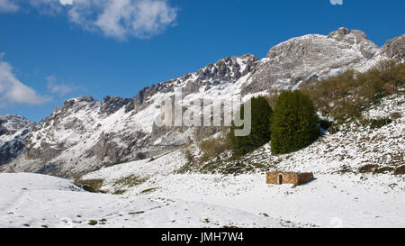 A snowy panoramic view of a teito, which is a typical hut, and surrounding peaks at Somiedo Natural Park (Asturias, Spain) Stock Photo