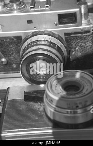 closeup of two old vintage retro film cameras with lens attached. black and white image Stock Photo