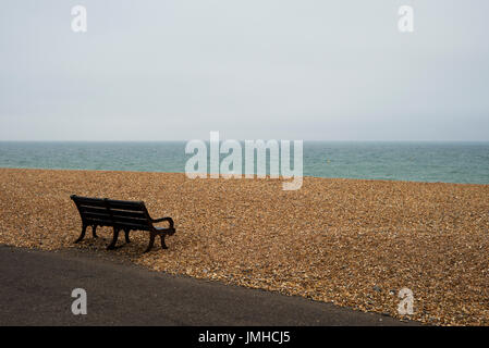 Solitary bench on empty beach, Hove, UK Stock Photo