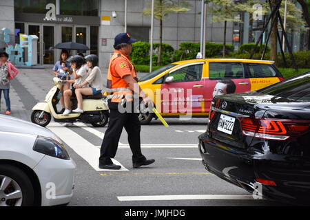 A volunteer traffic policeman who is actually a taxi driver is helping direct traffic to help the public, Taipei, Taiwan. Stock Photo