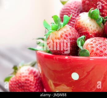 Colored photo of some strawberries inside a red cup Stock Photo
