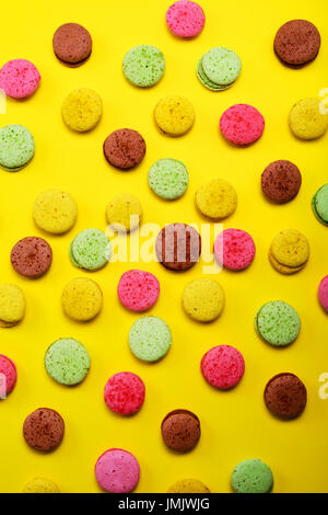 Colored almond cookies macarons on a yellow background, close up Stock Photo