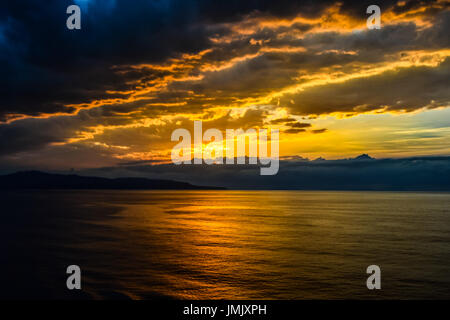 Beautiful sunset off the island of Sicily Italy in the Mediterranean sea with yellow skies and dark clouds moving a storm in. Stock Photo