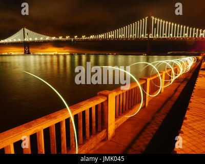 New Bay Bridge at Night as Seen from the Embarcadero in San Francisco, California with Circular Light Painting in the Foreground Stock Photo