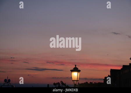 Street lamp illuminating the way against the setting sky in Venice, Italy Stock Photo