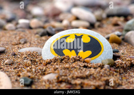 Paphos, Cyprus - November 22, 2016 Pebble with painted sign Batman on beach sand. Stock Photo