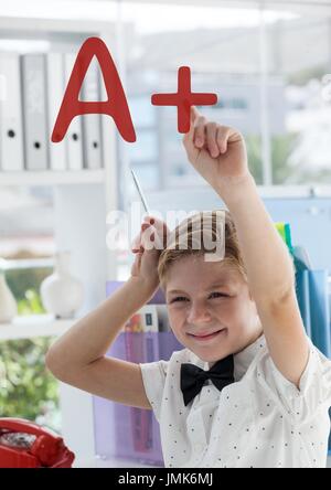 Digital composite of Happy office kid boy pointing at an A+ text Stock Photo