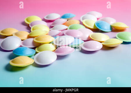 flying saucer multi coloured candy sweets on a gradient background pink and blue. Minimal color still life photography Stock Photo