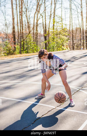 Young fit woman bouncing basketball in playground Stock Photo