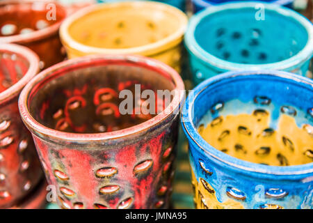 Colorful artistic ceramic flower pots with holes painted blue and red Stock Photo