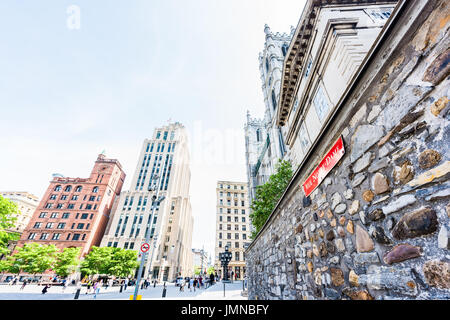 Montreal, Canada - May 28, 2017: Old town area with Notre Dame Basilica street sign in red during day on stone wall outside in Quebec region city Stock Photo