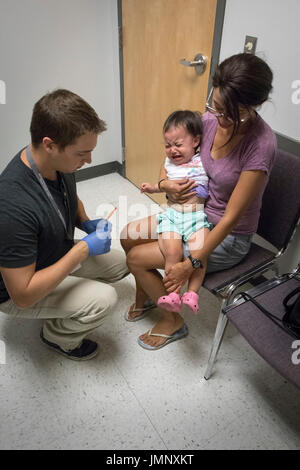 baby being held by anxious mother receiving vaccination injection in doctor's office Stock Photo