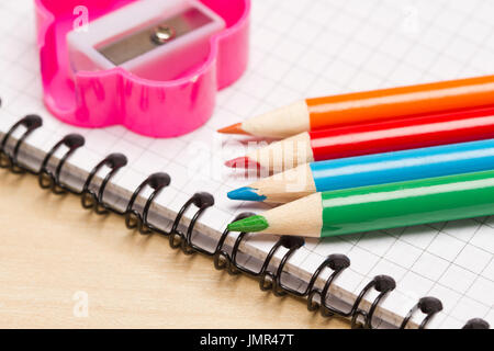 Colored pencils,notebook and pencils sharpener on table Stock Photo