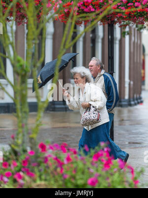 Elderly lady woman in the rain and wind holding an umbrella. Stock Photo