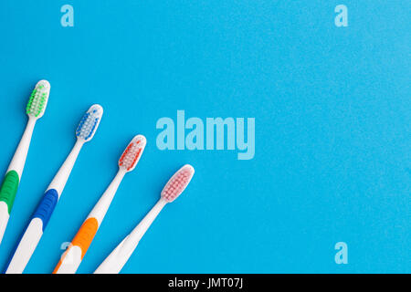 Four multicolored toothbrushes on empty blue background, place for words Stock Photo
