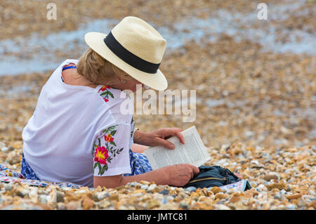 Woman reading a book on the beach at Lyme Regis, Dorset in July Stock Photo