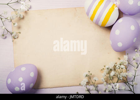 Colorful Easter eggs and flowers on old sheet of paper with space for text. Top view Stock Photo