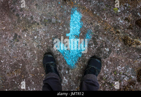 Woman standing at a blue painted direction arrow on the ground Stock Photo