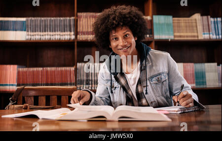 Young confident student learning from books in library. university student studying in the library. Stock Photo