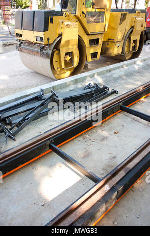 City street rail tracks for trams, road steel drum roller a road making engineering vehicle used to compact soil in the construction industry