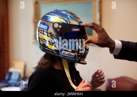 Washington, DC - August 19, 2009 -- United States President Barack Obama's personal secretary, Katie Johnson, tries on Jimmie Johnson's NASCAR helmet as the President's personal aide Reggie Love lifts the visor, August 19, 2009. .Mandatory Credit: Pete Souza - White House via CNP