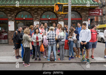 A female guide speaking to tourists on a tour of Chinatown and on Mott street. In Manhattan, New York City. Stock Photo