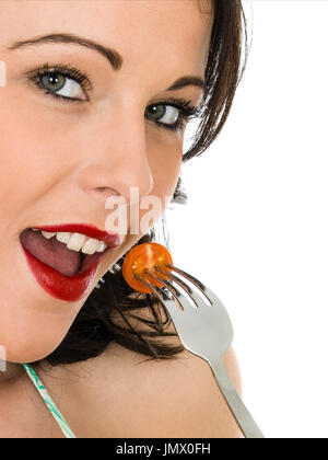 Portrait of a Young Woman Eating a Single Cherry Tomato Against a White Background Stock Photo