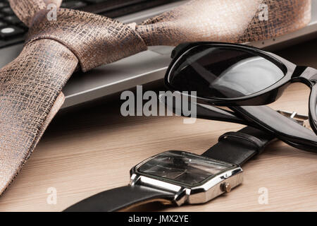 Close-up, focus on sunglasses with laptop and tie. Desktop Space Stock Photo
