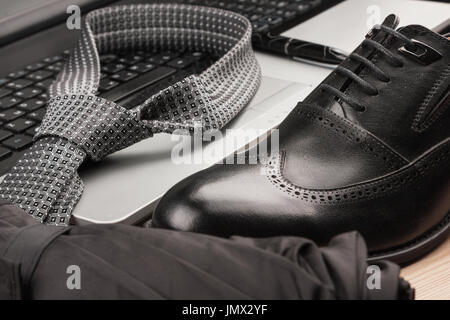 Close-up, focus on shoes with laptop and tie. Desktop Space Stock Photo