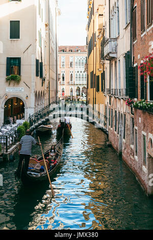 Gondolas on a narrow canal leading to Grand Canal in Venice. Gondola rides and tours are the city's iconic features and are very popular among tourist Stock Photo