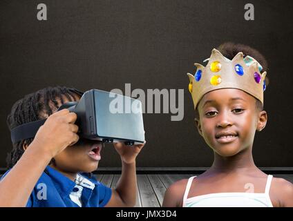 Digital composite of Boy with VR Headset and girl with crown in front of blackboard Stock Photo