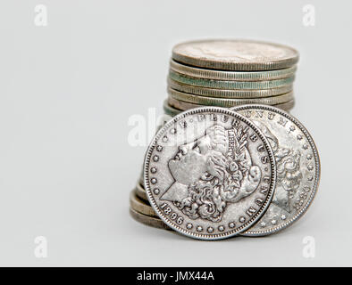 1896 and 1880 Morgan Dollar coins lean on a stack of other Morgans. Stock Photo