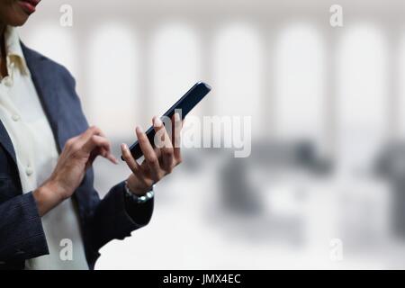 Digital composite of Business woman using a phone against office background Stock Photo